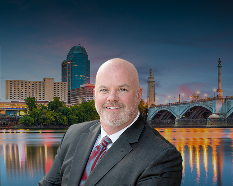 Foto of Dan Daly in front of Springfield, Massachussetts, USA downtown skyline on the river